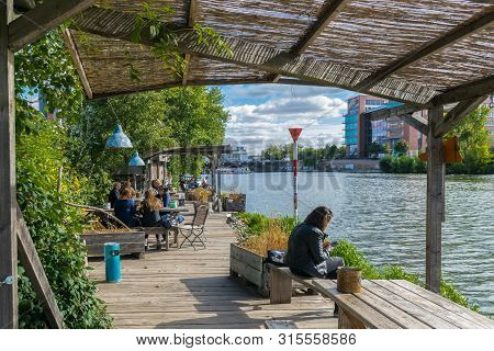 Berlin, Germany - September 26, 2018: Berliners Relaxing At A Wooden Platform By The Margins Of The 