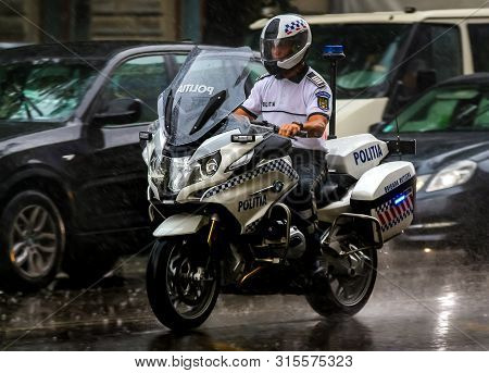 Bucharest, Romania - August 01, 2019: A Policeman Ride A Bmw R 1200 Rt Authority Motorcycle, In Rain