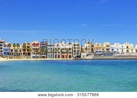 Pretty Bay Beach In Birzebbuga With Colorful Houses On Coastline, Sandy Beach And Mediterranean Sea,