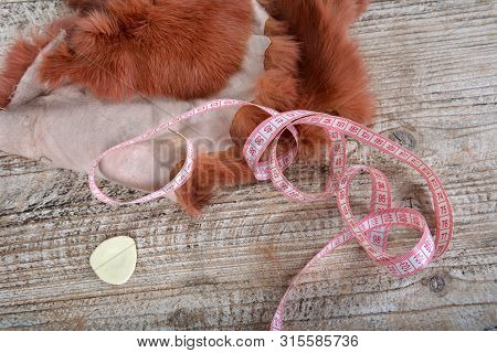 Brown Rabbit Fur For Sewing, Centimeter And Chalk On Wooden Background.