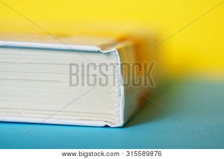 A Closed Thick White Book Or Diary Lies On A Yellow And Blue Background. College Or School Science L