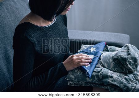 Cropped View Of Woman On Couch With Military Clothing And Foded American Flag At Home