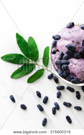 Ice-cream Decorated With Fresh Berries Of A Honeysuckle And Green Leaves On White Background. Top Vi