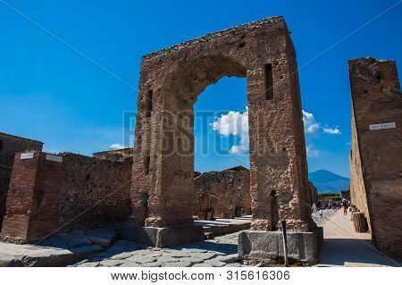 Pompeii, Italy - April, 2018: Tourists At The Arch Of Caligula In The Ancient City Of Pompeii