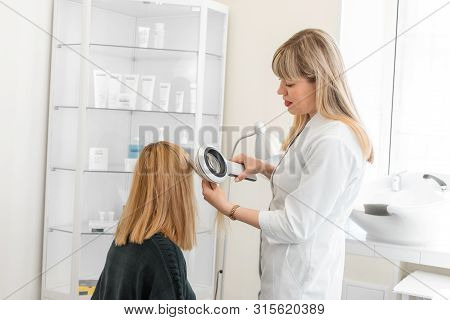 Physician Trichologist Dermatologist Examines The State Of The Patient's Hair And Hair Roots With A 