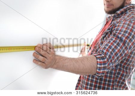 Man Measuring White Wall, Closeup. Construction Tool