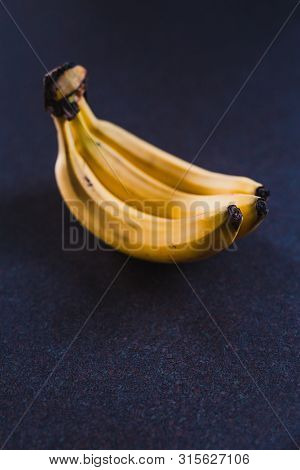 Three Bananas On Dark Background Shot At Shallow Depth Of Field