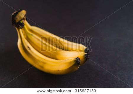 Three Bananas On Dark Background Shot At Shallow Depth Of Field