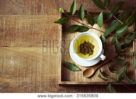 A cup of green tea on wooden tray  with green leaves. Healthy lifestyle. Copy space