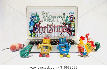 retro tin toys looking at a there friends celerbrating Christmas on a laptop computer 
