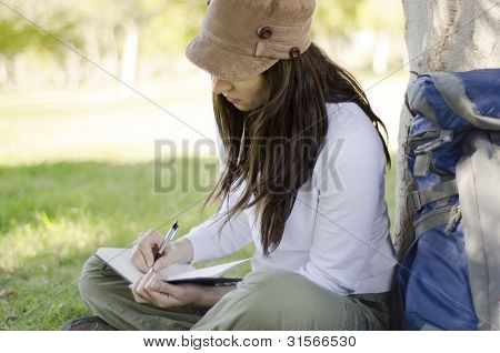 Escritura en diario de viaje de la mujer joven