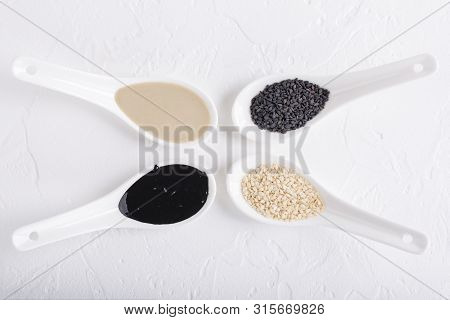Black Tahini And White Tahini Sauce In Spoons On White Background. Natural Paste Made From Sesame Se