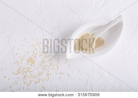 Tahini Sauce And Sesame Seeds On White Background. Natural Paste Made From Sesame Seeds. Copy Space.