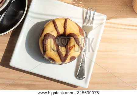 Chocolate-coated Donuts In A White Plate On A Wooden Floor