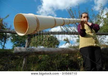Vrouw speelt de traditionele Roemeense alpenhorn