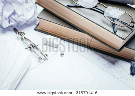 Books, Glasses, Pencil, Compass And Rolls Of Drawings On The Details Of Industrial Drawings
