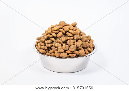 Full Cup With A Slide Of Dry Pet Food Isolated On White Background. Metal Bowl For Cat Or Dog. The C
