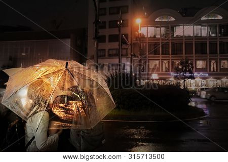 Osaka,japan,15 July 2019, The Couples Will Kiss Under The Transparent Umbrella In Night Street While