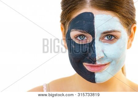 Woman With Clay Carbo Black Mask On Half Face And White Mud On Second Half. Girl Taking Care Of Oily