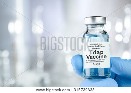 Healthcare concept with a hand in blue medical gloves holding Tap, tetanus, diptheria, and pertussis, vaccine vial