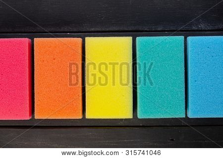 Sponges Of Different Colors In Dark Background, Top View. Five Pieces Of Dishcloth Laid In Row On Da