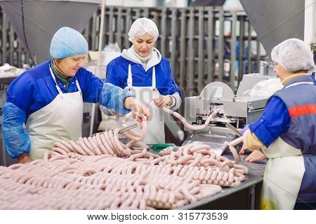 Butchers Processing Sausages At The Meat Factory.