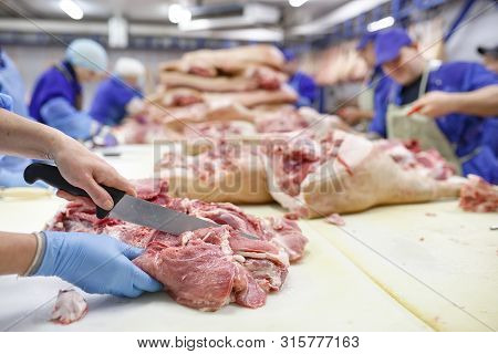 Cutting Meat In Slaughterhouse At The Meat Manufacturing.