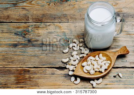 Fresh Organic Raw Vegan Cashew Milk With Cashew Nuts On Wodden Background.