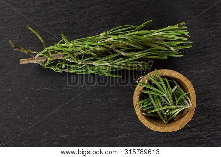 One Whole Lot Of Pieces Of Fresh Evergreen Sprig Of Rosemary In A Wooden Bowl Flatlay On Grey Stone