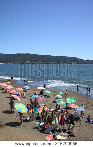 Niebla, Chile - February 2, 2016: Parasol Rental And Visitors Enjoying The Sun And The Water On The 
