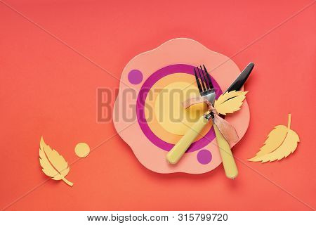 Autumn Concept Flat Lay In Bold Colors With Plate, Fork, Knife And Decorative Autumn Leaves In Yello