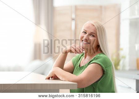 Portrait Of Happy Mature Woman At Table Indoors