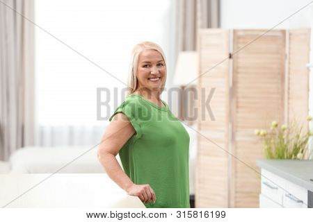 Portrait Of Happy Mature Woman At Table Indoors
