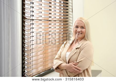 Portrait Of Happy Mature Woman Near Window Indoors