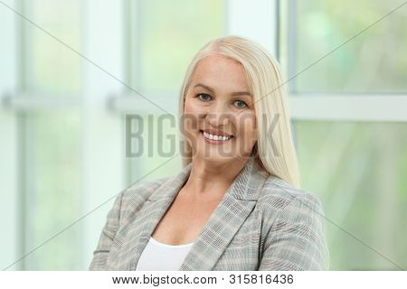 Portrait Of Happy Mature Woman Near Window Indoors