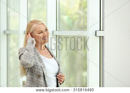 Portrait Of Happy Mature Woman Near Window Indoors