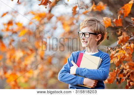 Positive Smiling Boy In Glasses Holding Book Ready For A New School Year, Back To School Concept, Fa