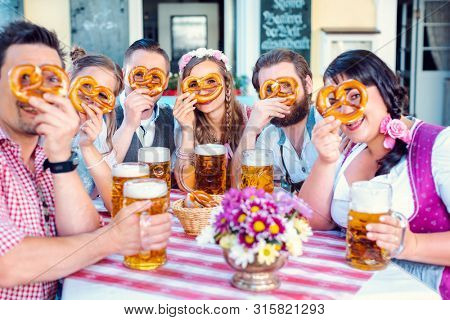 Group in Bavarian beer garden looking through pretzel holes at the camera