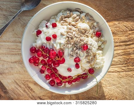 Rustic Cottage Cheese With Seeds And Sour Cream In A Deep White Plate On A Wooden Spile, From The Up