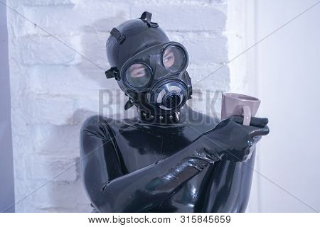 Morning Cup Of Tea Breakfast. Fetish Male In Rubber Black Suit At White Windowsill.