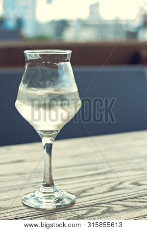 A Glass Of Cold White Wine On The Table On The Terrace Of A Summer Cafe