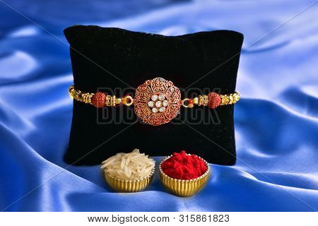 Raksha Bandhan, Rakhi With Roli Chawal In Blue Silk Background