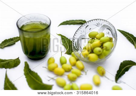 Detox Or Detoxifying Drink Of Neem Fruit In A Glass Isolated On White Along With Some Neem Fruit Or