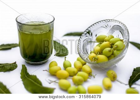 Detox Or Detoxifying Drink Of Neem Fruit In A Glass Isolated On White Along With Some Neem Fruit Or