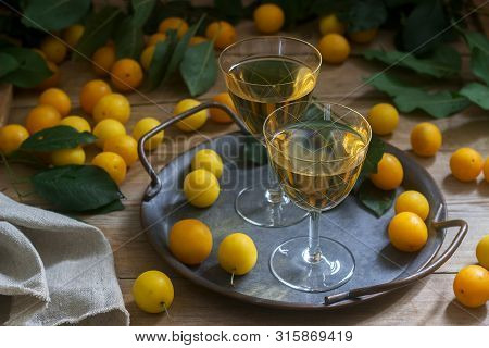 Cherry Plum Liqueur In Small Glasses And Cherry Plum On A Wooden Background. Rustic Style.