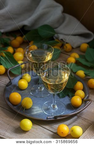 Cherry Plum Liqueur In Small Glasses And Cherry Plum On A Wooden Background. Rustic Style.