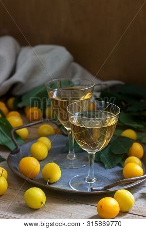 Cherry Plum Liqueur In Small Glasses And Cherry Plum On A Wooden Background. Rustic Style.