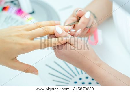Woman having her finger nails cut during manicure with scissors