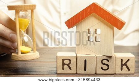 Wooden Blocks With The Word Risk, The House And The Clock. The Concept Of Non-payment Of Interest Ra