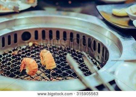 People Grilling Meat On A Smokeless Barbecue Grill In A Restaurant. Selective Focus On Shrimps.